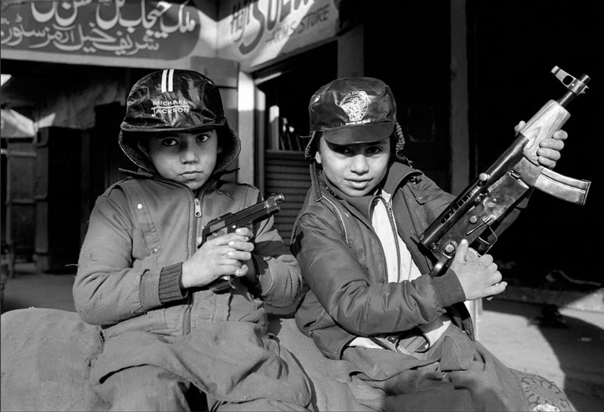 Two young boys holding copies of weapons outside their father's gun shop (Два мальчик, которые держат копии оружия за пределами оружейного магазина их отца), 1989