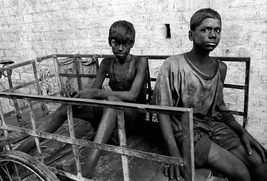 Two young boys covered in coal dust sitting on the bicycle cart they use to transport coal (Два мальчика, покрытые угольной пылью, сидят на велосипедной тележке, которую они используют для транспортировки угля), 1996