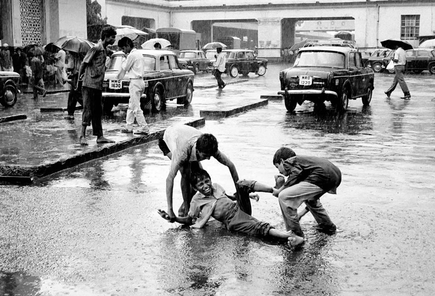 Street children enjoying the first monsoon rain outside Bombay Central train station