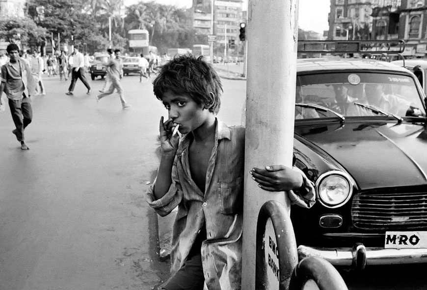 Sangay, a street child from Delhi, smoking the remainder of a cigarette which he found in the street outside Victoria Terminus station