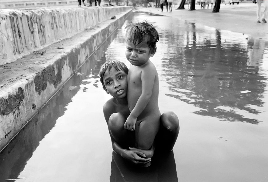 Street children playing in water after monsoon rain on Chowpatti beach