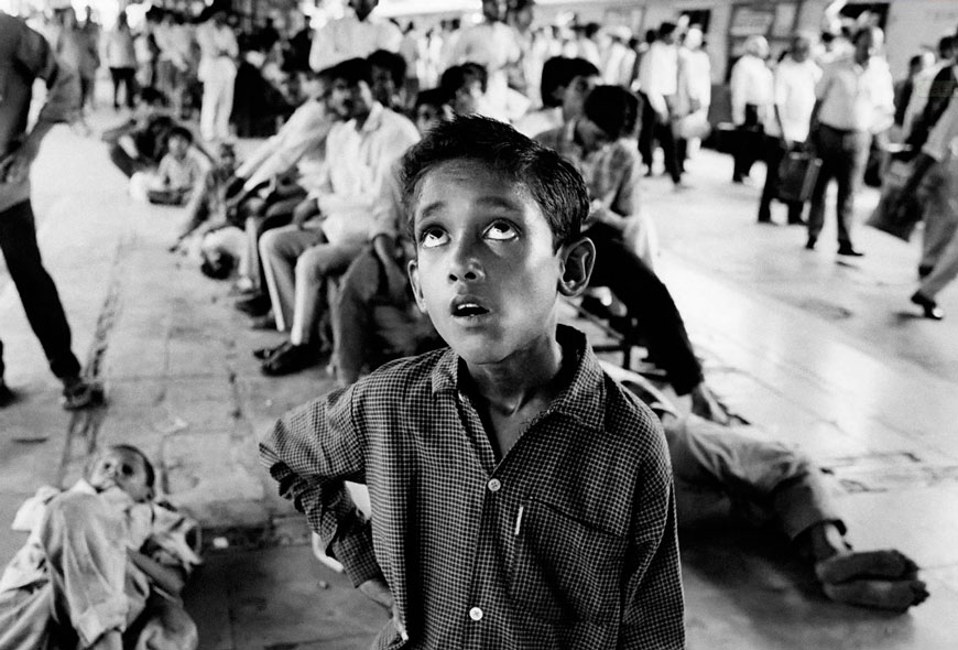 A street child mesmerised by a Hindi film on a TV screen at Dadar train station