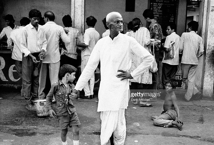 A street child sits near a food stall waiting for leftovers near Victoria Terminus station