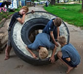 Children play on a tire being used to block the entrance (Дети играют на покрышке, служащей преградой для въезда в посёлок)