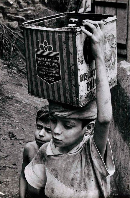 Flavio da Silva carrying a can of water collected from the stream at the bottom of the hill (Флавио да Силва, несущий банки с водой, собранной в ручье у подножия холма)