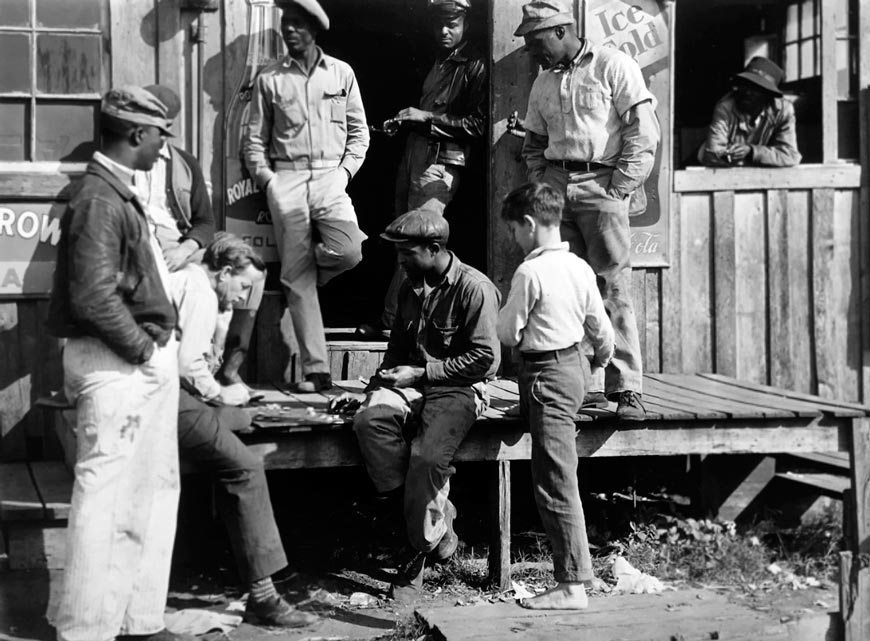 Migratory laborers playing checkers in front of juke joint during slack season for vegetable pickers (Мигрирующие рабочие играют в шашки перед приемным пунктом во время затишья для сборщиков овощей), February1941