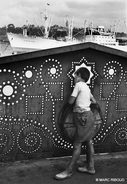 Through the lace of the Galata bridge, to the Golden Horn, does this poor little boy dream about big trips, 1955