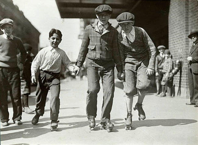 Three Children Hold Hands and Roller Skate Down Sidewalk (Три мальчика, держащихся за руки и катящихся на роликовых коньках по тротуару)