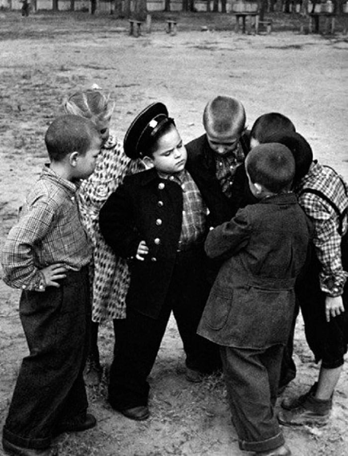 Первоклассник хвастается новой формой перед дворовыми друзьями (A first-grader shows off his new uniform to his yard friends), 1955