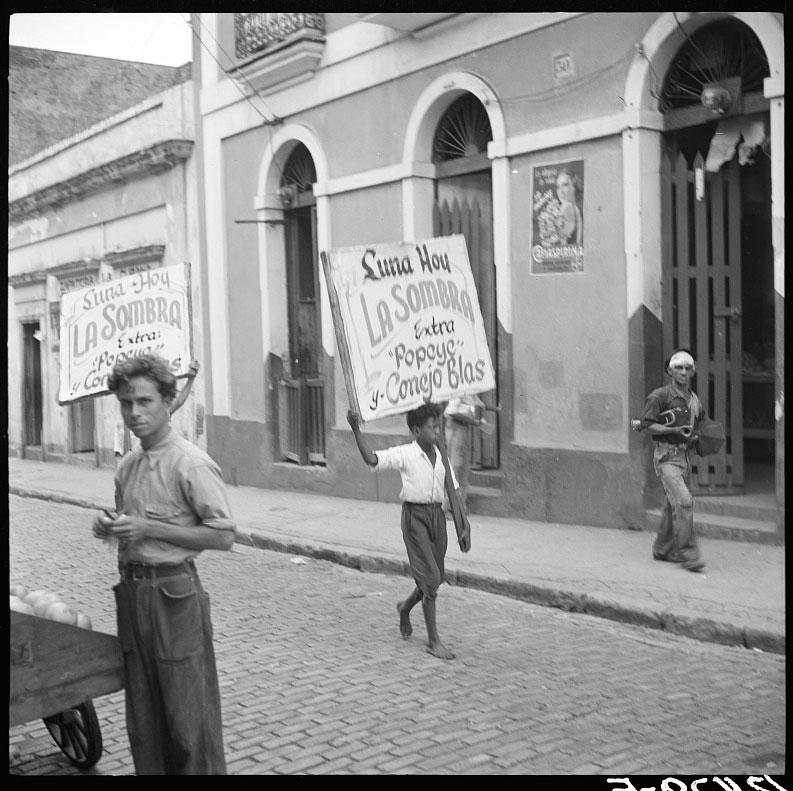 Boy carrying sign advertising a movie program (Мальчик, несущий рекламный плакат кинопоказов), Jan.1938