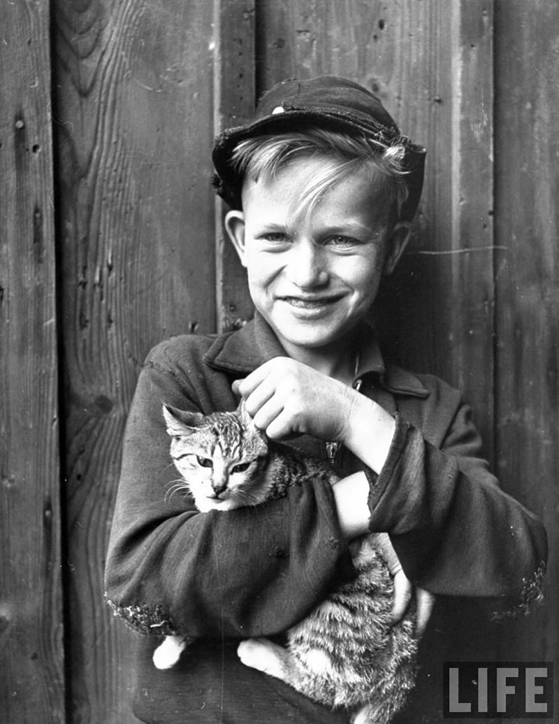 Village boy holding cat and smiling (Деревенский мальчик, держащий кошку и улыбающийся), August 1946