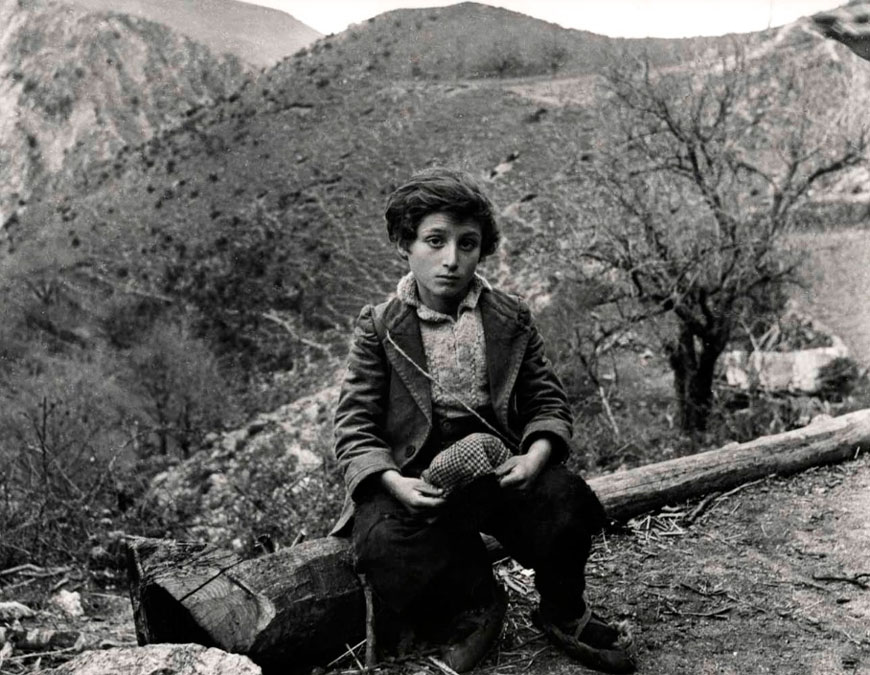 Young boy sitting on a fallen tree, around mountains and hills (Мальчик, сидящий на поваленном дереве среди гор и холмов), 1948