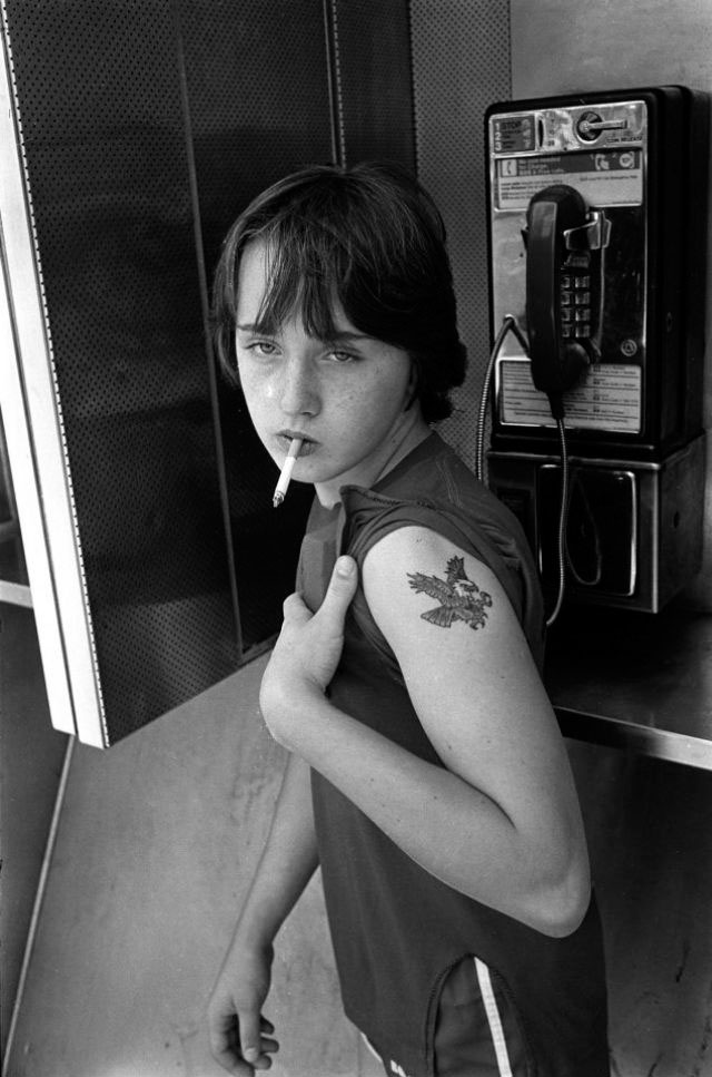 A teenage hustler smoking in a telephone booth (Юный хастлер курит в телефонной будке)