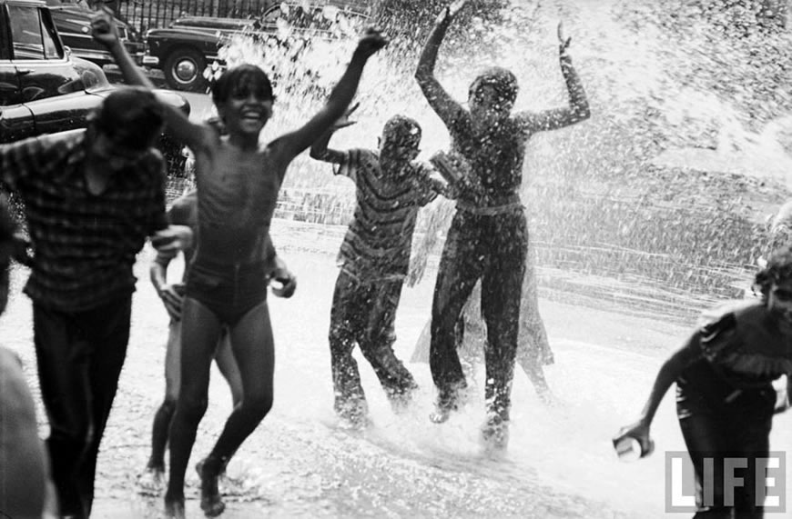 Children playing in the spray of an open fire hydrant to escape the fongoing heat wave, Aug.1953