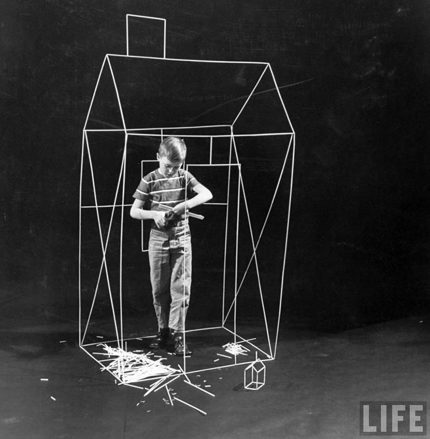 Boy using a pair of scissors snipping a straw on his project to his desired length, May.1956