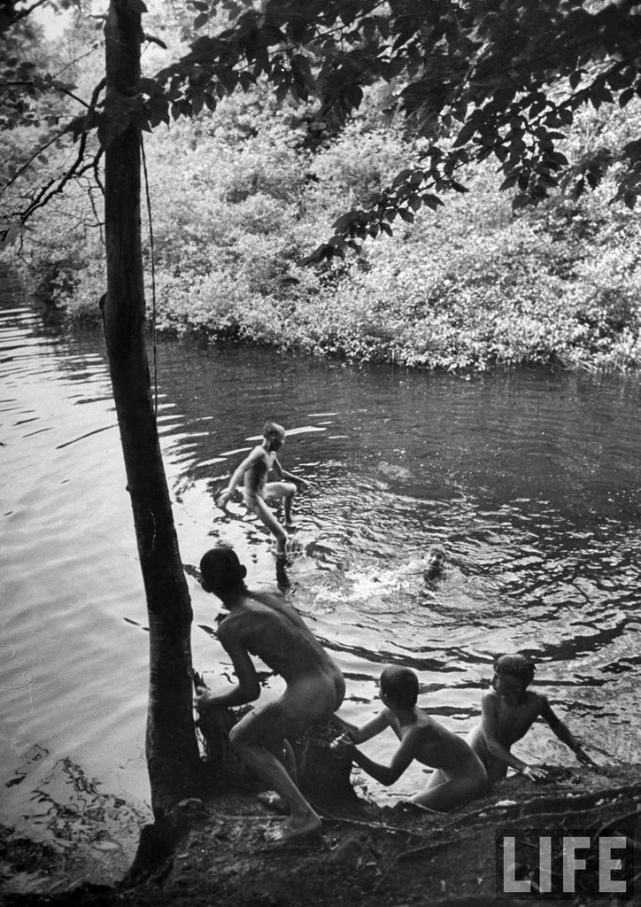 Young male skinny dippers frollicking in a favorite swimming hole on hot summer day, July 1948