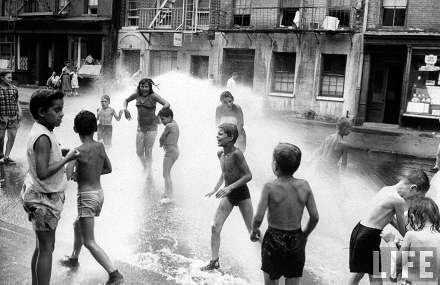 Children playing in the spray of an open fire hydrant to escape the fongoing heat wave, Aug.1953