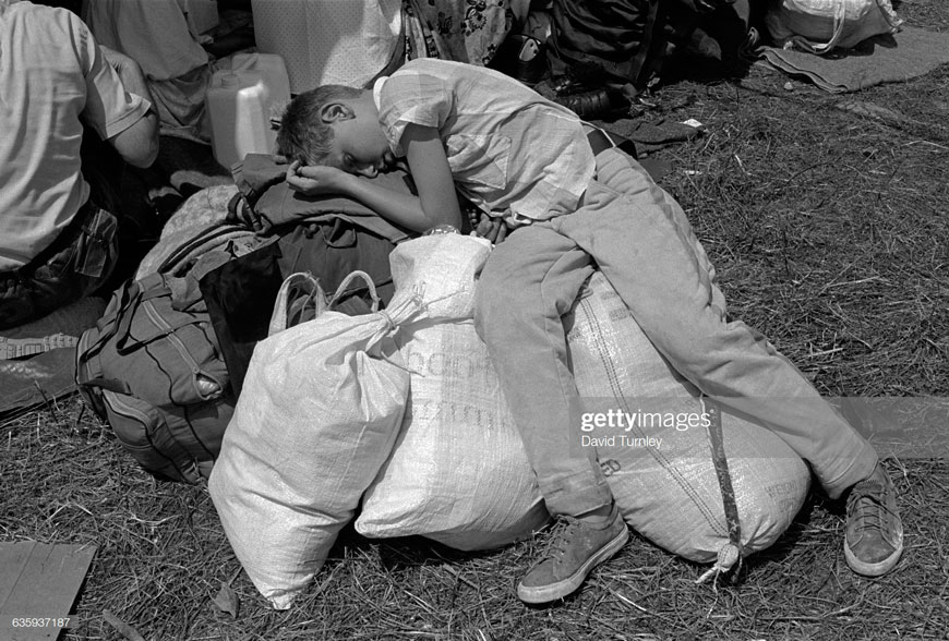 Refugee Boy Resting on Baggage (Мальчик-беженец отдыхает на багаже), 1995