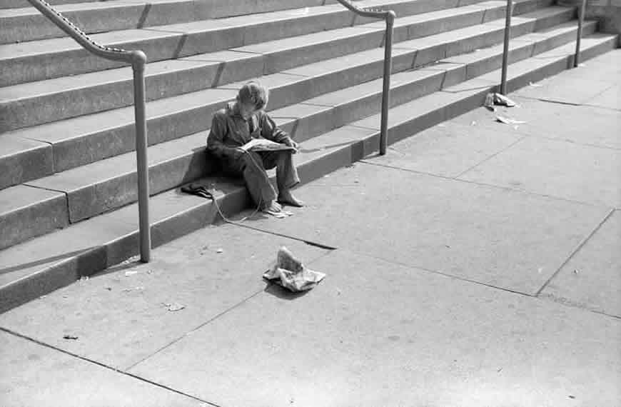 Boy reading funny paper on steps of public library (Мальчик читает занимательную газету на ступеньках публичной библиотеке)