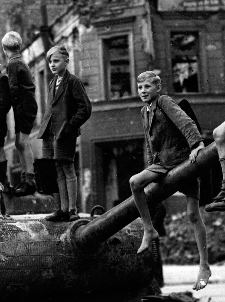 Children play on the bomb sites and wrecked tanks in Berlin, in the aftermath of the fighting in the city, 1945