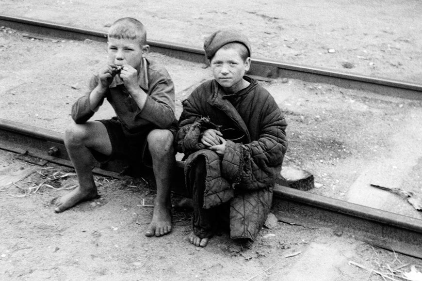 Two young raggedy dressed and barefooted Russian boys sitting on a railway track during World War II (Два оборванных и босых мальчика сидят на железнодорожных путях), 1941