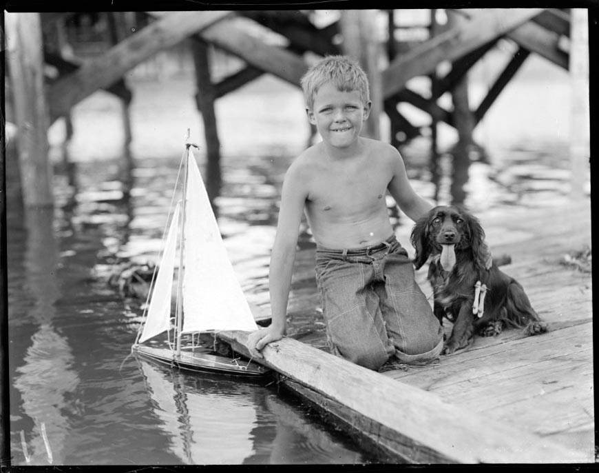 Boy and his dog play with toy sailboat (Мальчик и его собака играют с игрушечным корабликом), 1917-1934