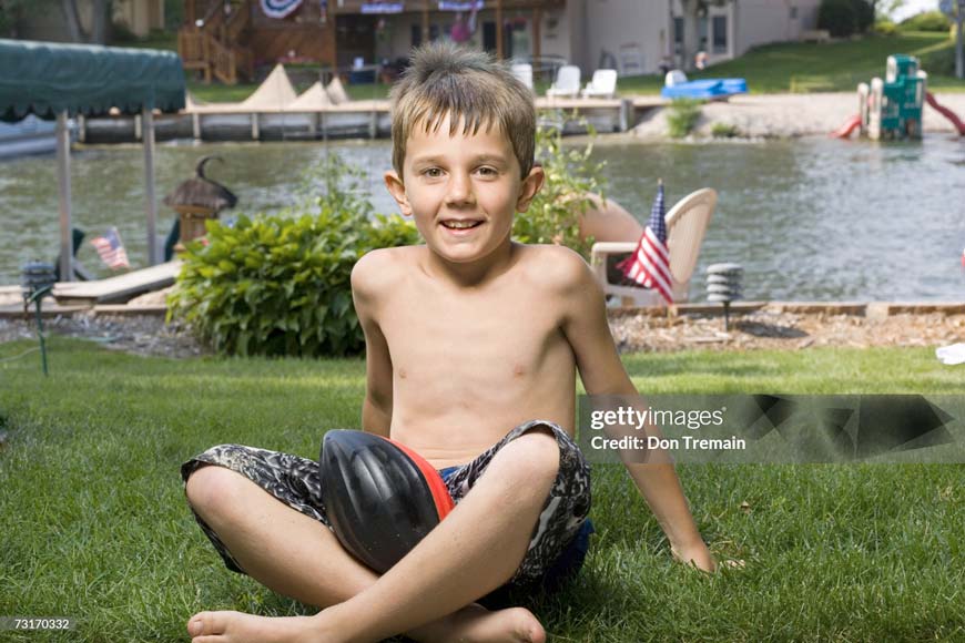 Boy sitting by lake on grass (Мальчик, сидящий у озера на траве)