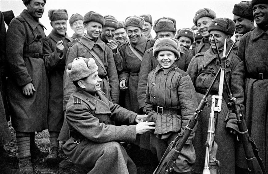 Сын полка Ваня Козлов в окружении красноармейцев на отдыхе (The son of the regiment, Vanya Kozlov, surrounded by Red Army soldiers on vacation), декабрь 1944